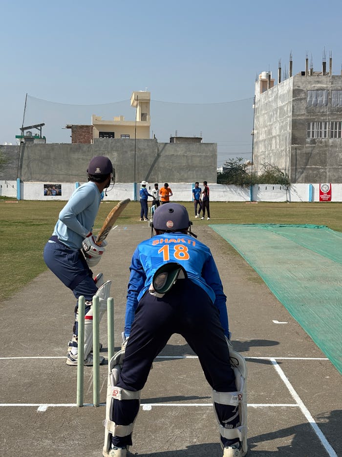 about-01 Young athletes playing cricket at a local field in Lucknow on a sunny day, showcasing teamwork and sportsmanship.